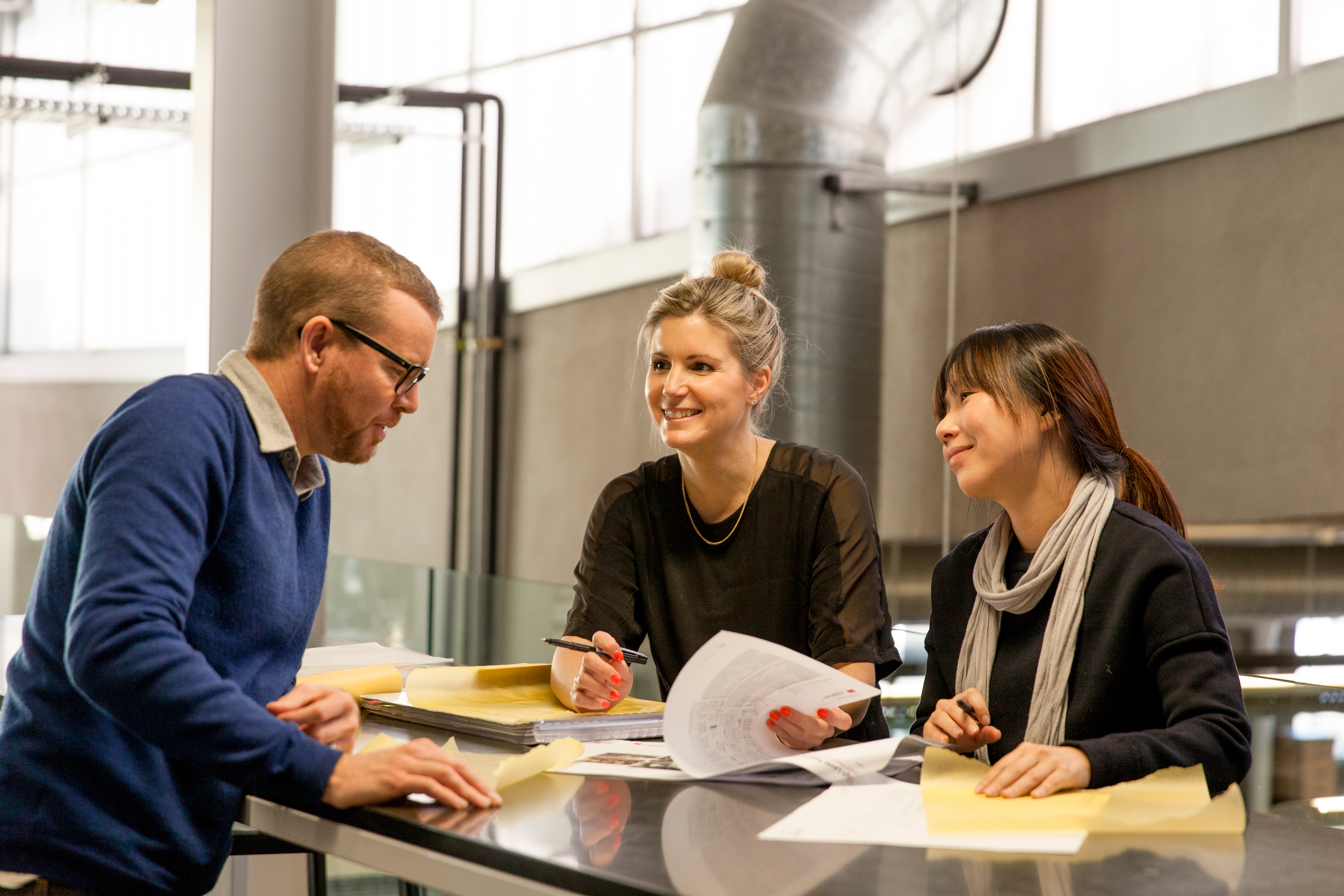 People around the table talking, looking at paper documents 